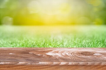 Empty rustic wooden table against blurred grass meadow with sun effect. can be used for display or montage your products. Mock up