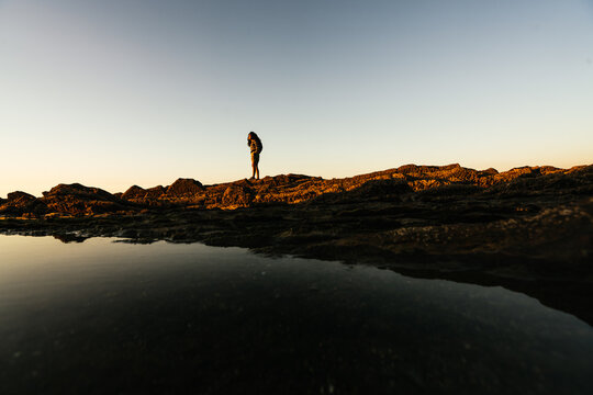 Silhouette of a woman looking at the sea, in a lovely sunset.