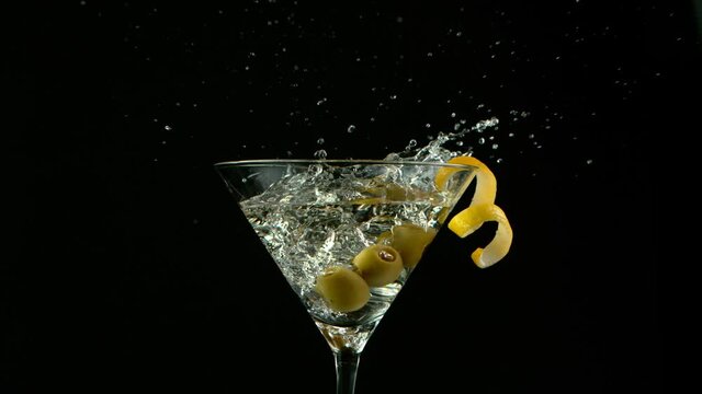 Super Slow motion shot of olives splashing into Dry Martini Drink