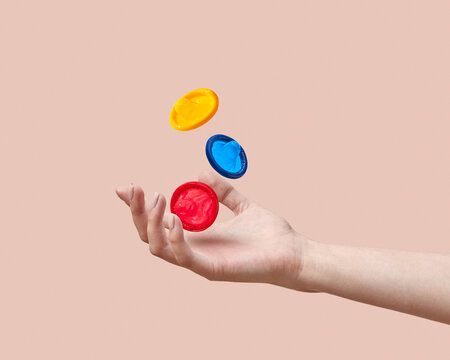 Close up shot of female`s hand juggling colorful condoms in the a
