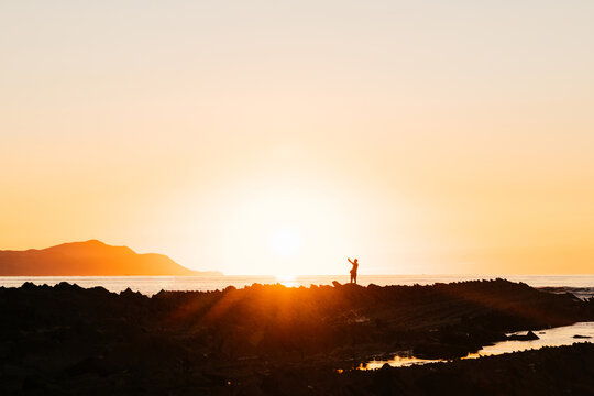Beautiful sunset and reflections. Silhouette of a person in the flysch of Zumaia, Spain