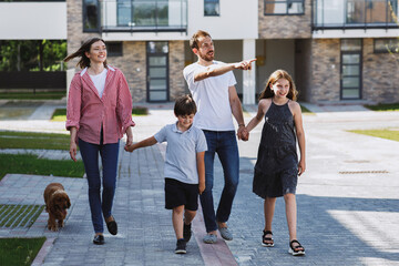 Happy family walking with dog in the street. The father, mother, daughter and son walking with dog