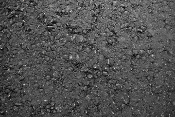 A smooth dark grey asphalt pavement texture with small rocks. Black bituminous waterproofing. Textured background.