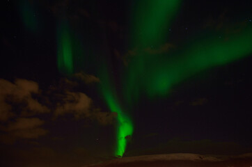 strong aurora borealis over snowy mountain in autumn