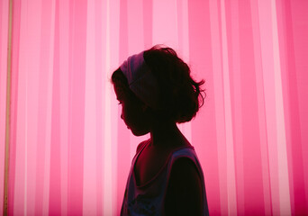Portrait of a little girl silhouette over pink neon lightened background
