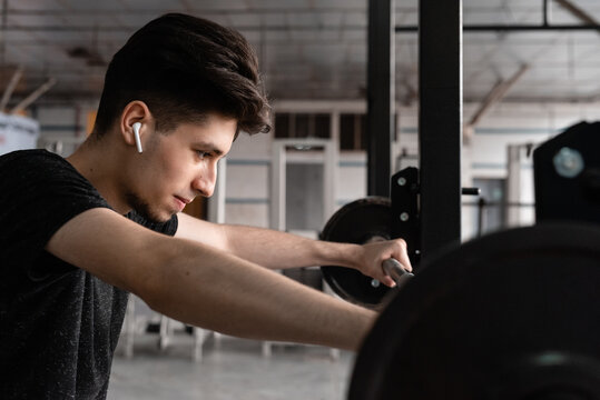 Young man exercising with barbell in gym