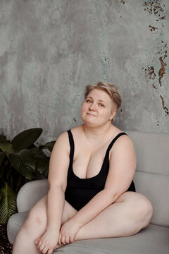 Huge blonde woman sitting on coach sofa and smiling.