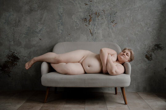 Front view of huge woman lying on gray sofa.