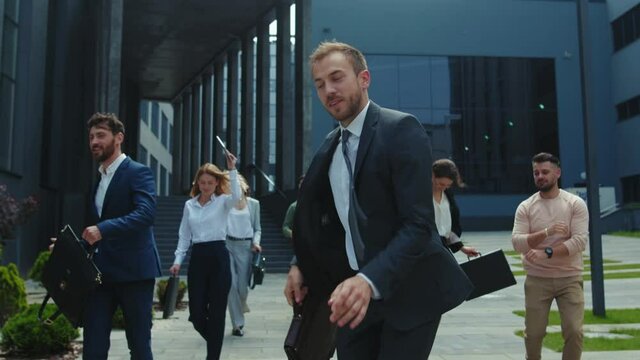 Multi-ethnic group of co-workers dancing funny on outdoor street. Happy satisfied business men and women with boss dancing on to rejoice corporate victory.