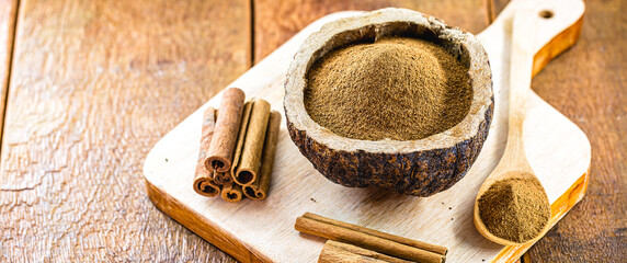 Fototapeta na wymiar powdered cinnamon in a rustic bowl, with pieces of cinnamon in the shell around, a culinary spice in a rustic photo.