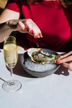 Woman pouring lemon juice on oyster and eating at served table