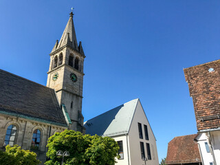 Fototapeta na wymiar Beautiful view of the bell tower of St. Michael's church beside a modern community building in Stuttgart-Degerloch under a clear blue sky.