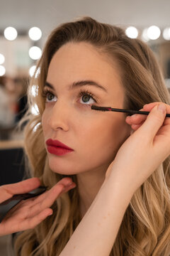 Crop hands applying mascara on lower eyelashes of model