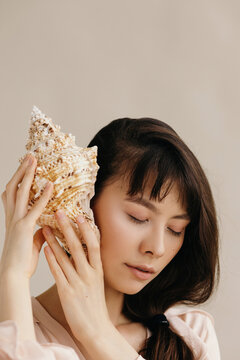 Ethnic woman listening to seashell