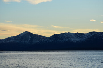 new snow on mountain with fjord in front and colourful dawn sky