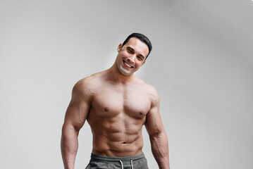 Fototapeta premium Sporty, sexy athlete smiling on a white background. Fitness