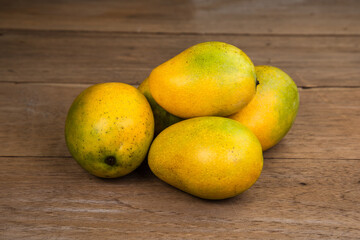 Ripe mango on wooden table. Tropical fruit. Group of fresh mango. Ripe yellow mangoes on wooden background