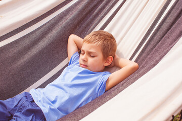 Preschoole boy lying in a hammock at summer day