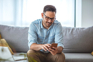 Man with spectacles relaxing sitting on couch while looking at mobile phone. Closeup of mature man...