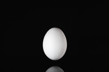 White egg levitating over a black glass table