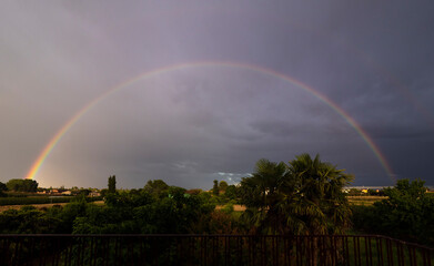 Rainbow with dark clouds and sun rays