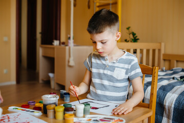 A cute little boy is playing and painting in his room. Recreation and entertainment. Stay at home