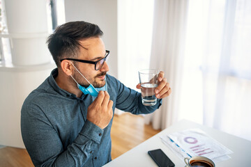 Young man in a protective mask in office or in home office. Man in the office wear mask to prevent corona virus. Protection virus and business concept.