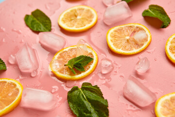 Composition with cut citrus fruits on pink background. Creative summer background composition with lemon slices, leaves mint and ice cubes. Minimal top down lemonade drink concept.Top view
