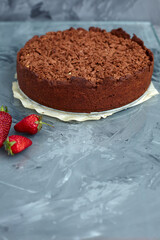 Chocolate cake is decorated with strawberry berries. Homemade cake. Pie on a grey background