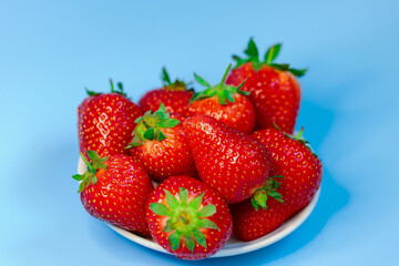 Fresh, ripe, delicious strawberries in a white Cup on a blue background. Background