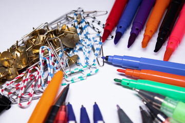 A pile of different stationery. multicolored markers, paper clips, pins, pencils, pens. High...