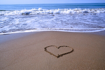 a painted heart on wet sand with a blurred background of sea waves