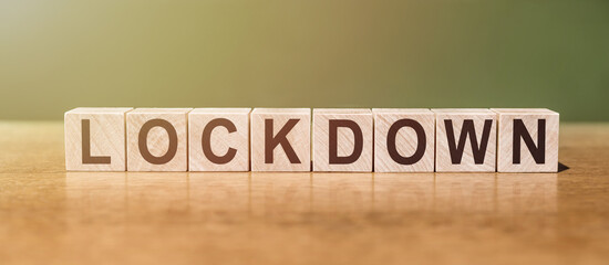 Lockdown word written on wooden blocks on wooden table. Concept for your design