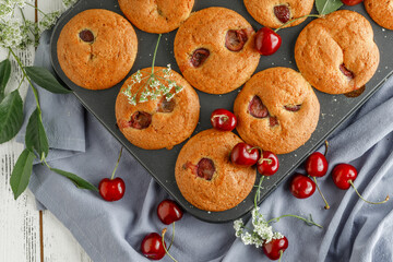 Freshly baked cherry muffins with fresh berries on a rustic wooden table
