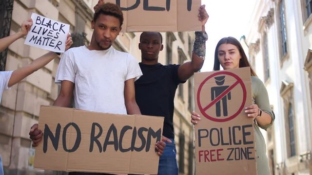 Peaceful protests in the USA. A rally against racism, social protests, young people, an interracial group of students standing in the middle of the street with posters no racism and police free zone