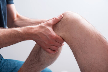 Man making deep massage near knee wit both hands.