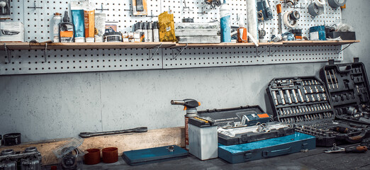 Moto workshop with hand mechanic tools kit. Workbench with sets of keys box, screwdrivers, electrical tape, on wall Table with motorcycle parts, vise. Workspace for auto mechanic. Banner for web site