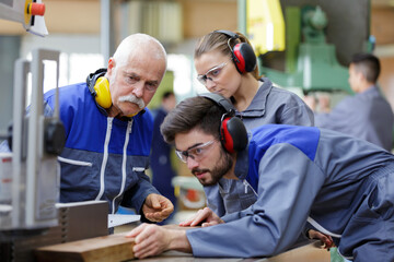 senior engineer instructing apprentices at machine bench