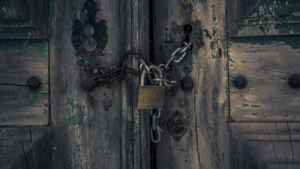 Texture of an old door closed with padlock and chain in a European architecture in the interior of Portugal