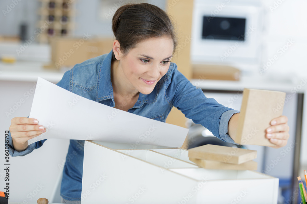 Wall mural confident woman following instructions to assemble furniture