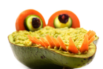 Funny alligator made of avocado with dip, cucumbers eyes and teeth made of carrots. Healthy food made for kids.