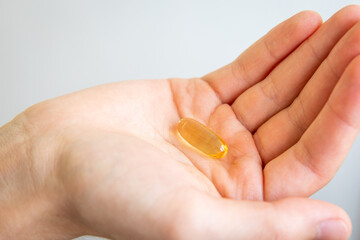 Yellow capsules of vitamin omega 3 in your hand. Biologically active additive. Fish oil in tablets. Medical support and treatment.