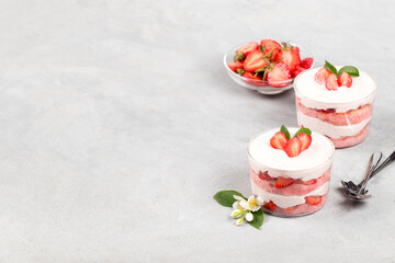 Obraz na płótnie Canvas Tiramisu cream strawberry dessert with sponge sticks in a glass Cup on a light background copy space