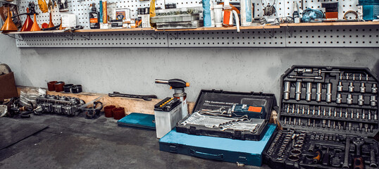 Garage with large workbench with professional wrenches in box and spare parts. Maintenance station, motorcycle, car repair, mechanical keys on wall, set of tools kit in workshop. Banner for web site