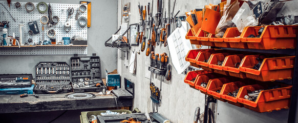 Garage with large workbench with professional wrenches in box and spare parts. Maintenance station, motorcycle, car repair, mechanical keys on wall, set of tools kit in workshop. Banner for web site