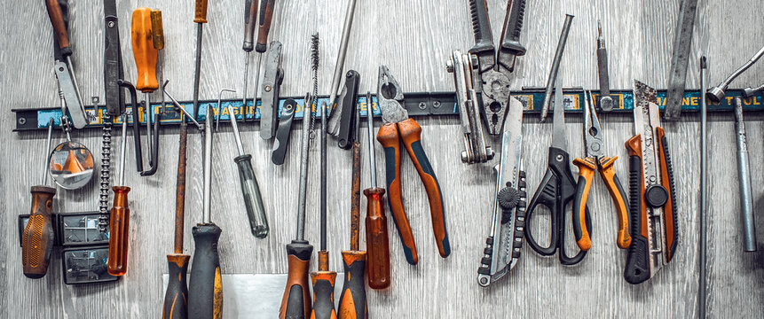 Maintenance station, motorcycle repair, mechanical equipment, tools in workshop. Manual machine tool on wall in garage. Knives, pliers, screwdrivers, scissors wrenches close-up. Banner for web site