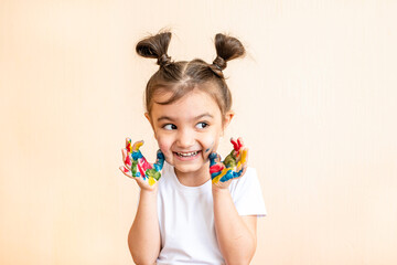 
joyful little girl with painted hands. the child joyfully shows his palms painted with paints. painted children's palms