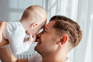 happy father holding adorable boy baby face to face