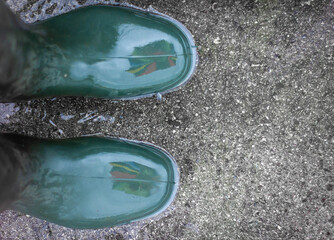 Ein Paar Schuhe Gummistiefel in einer Regenlache Wasserpfütze