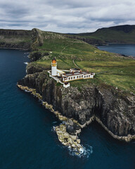 Old historic Neist Point Lighthouse in Scotland UK. Lighthouse on a cliff island in the middle of the ocean. Top view photo of a drone.